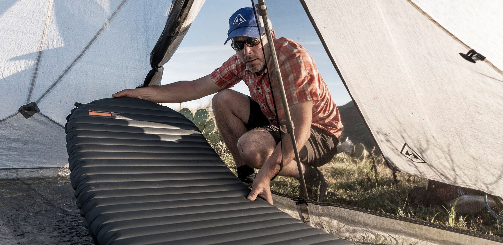 A man putting an air mattress into a tent.
