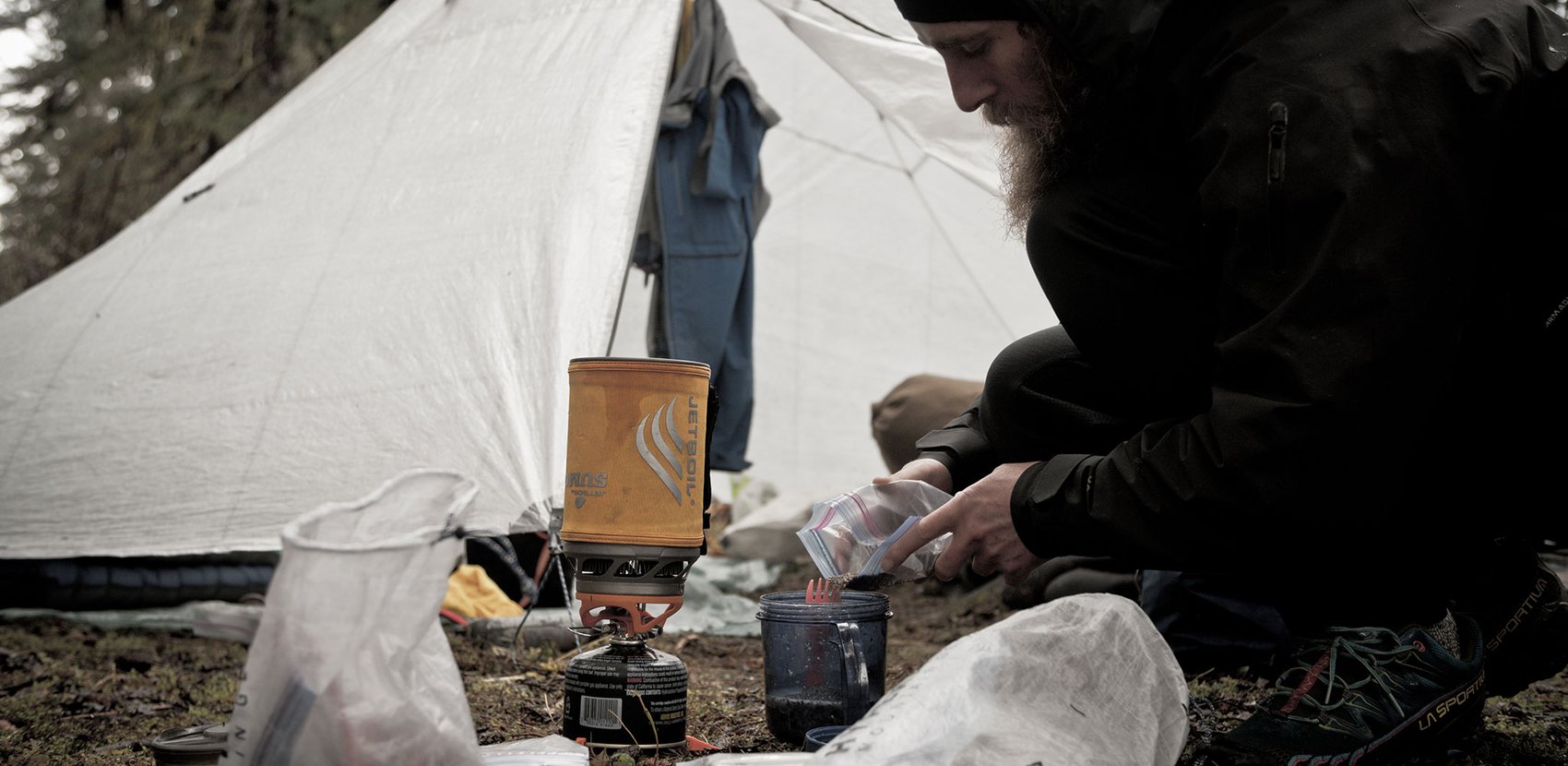 A man is preparing food in front of a tent.
