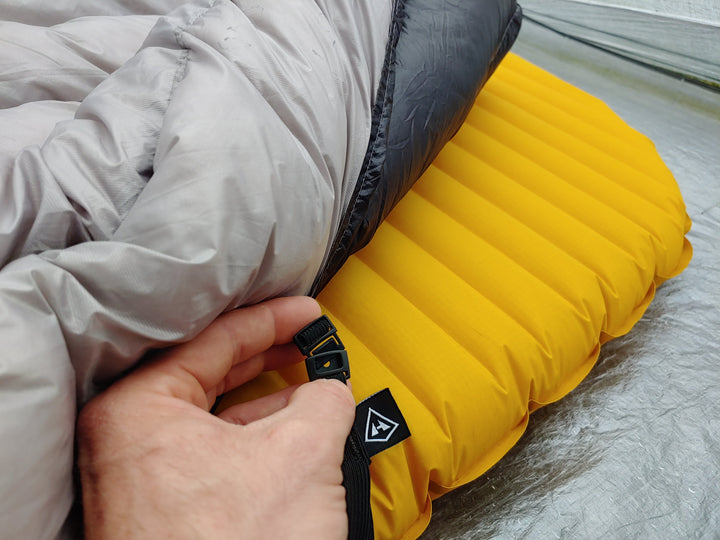 A person is putting a sleeping bag on top of a tent.