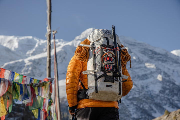 A man with a backpack in front of a mountain.
