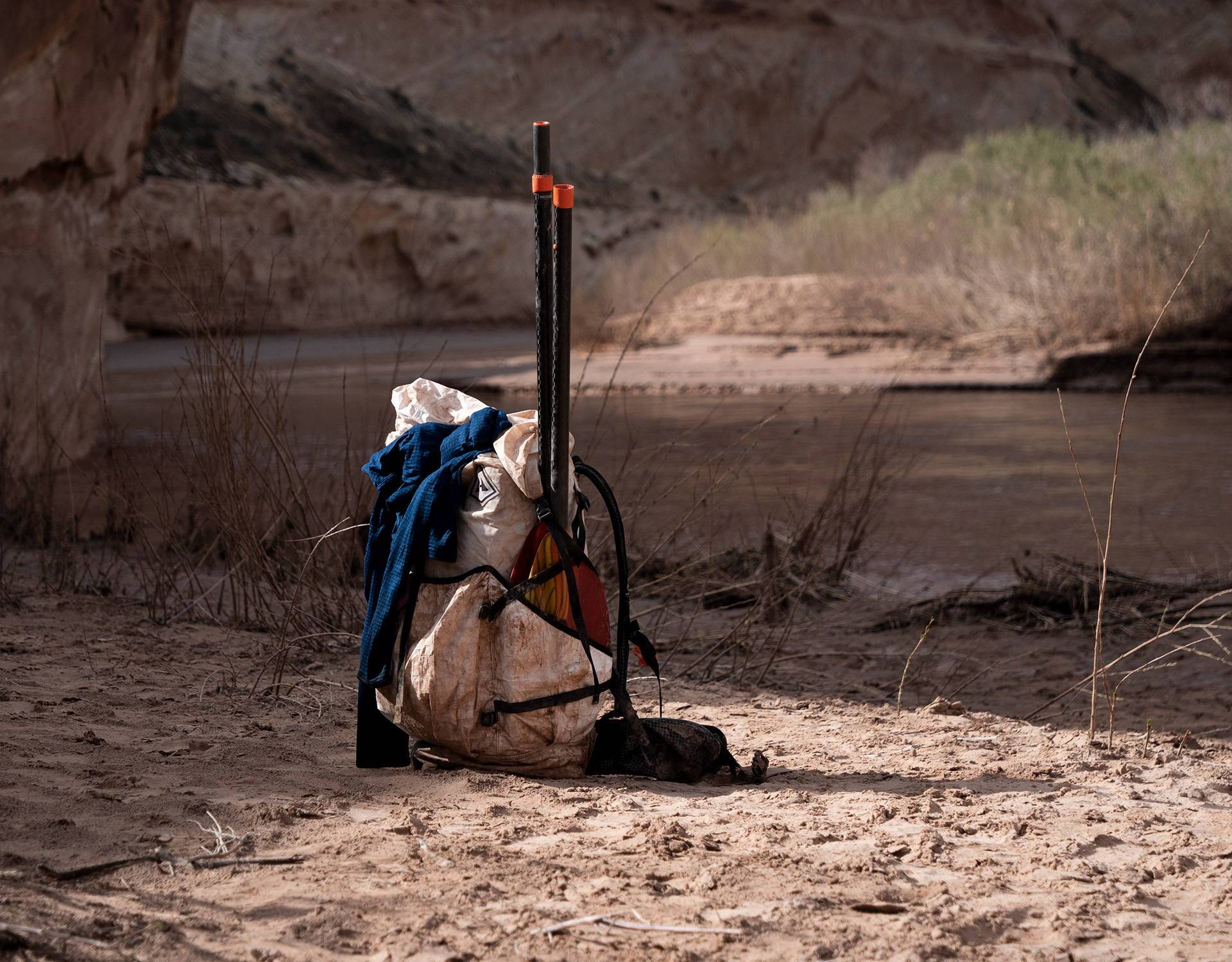 A backpack sitting on the side of a river.