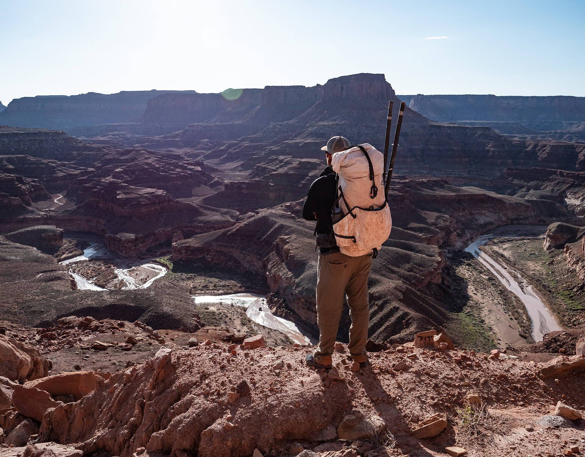 A man standing on a cliff overlooking a canyon.