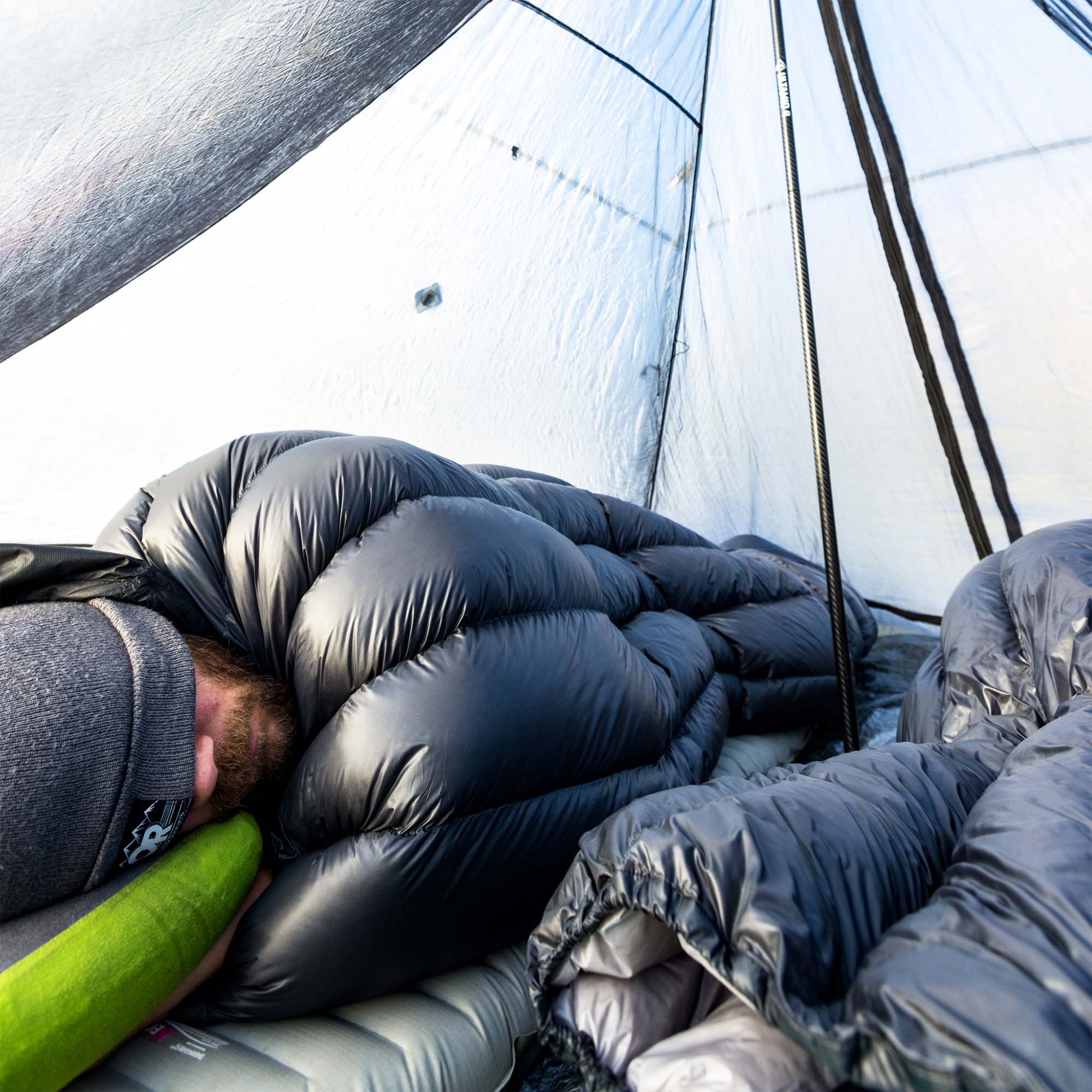 A man sleeping in a sleeping bag in a tent.