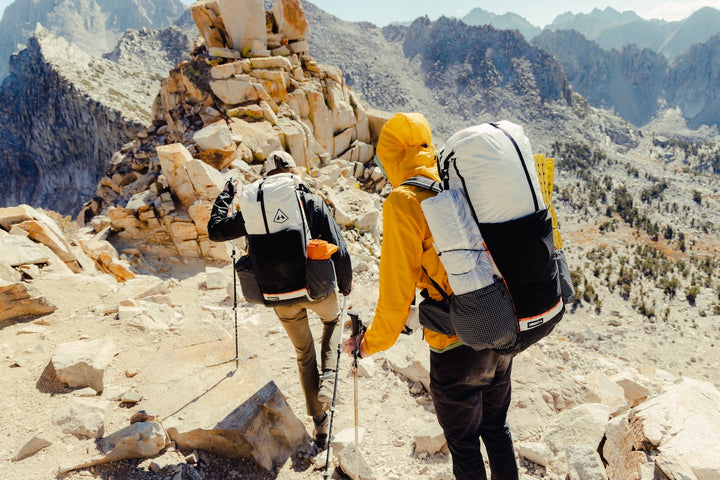 Two people hiking in the mountains with backpacks.