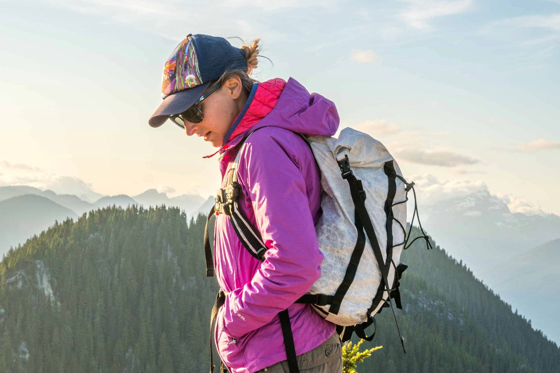 A woman with a backpack standing on top of a mountain.