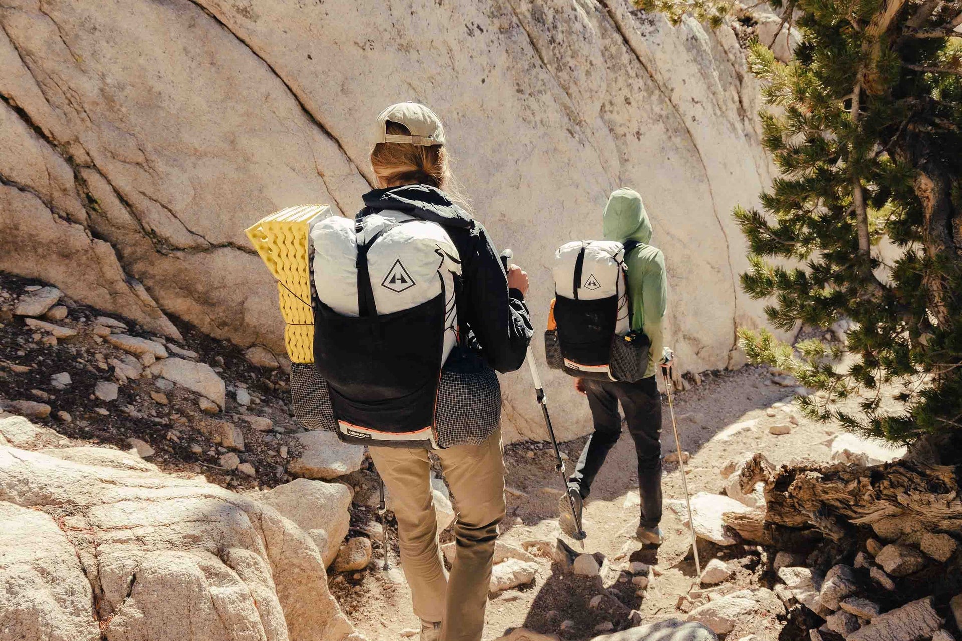 Two people walking up a rocky trail with backpacks.