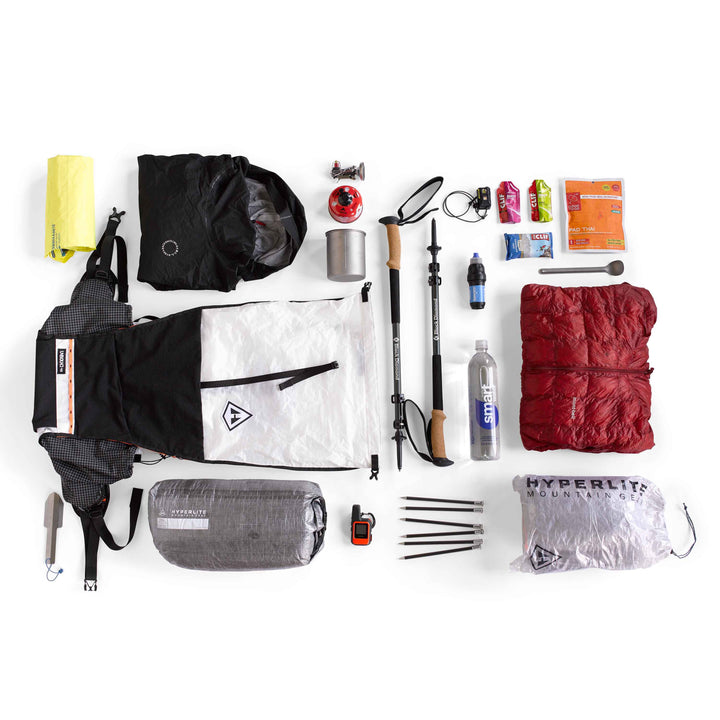 The contents of a backpack are laid out on a white surface.