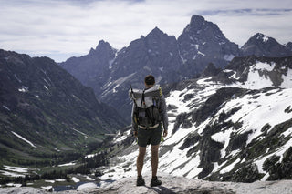 A person standing on top of a mountain with a backpack.