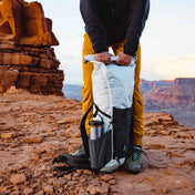 Hiker utilizing the roll top closure system of the Hyperlite Mountain Gear Elevate 22