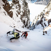 Using ice tools, two skiiers ascend a snowy slope in preparation to ski a nice line wearing the Hyperlite Mountain Gear Crux 40