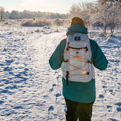 Hiker wearing Hyperlite Mountain Gear's Daybreak 17 Pack in White in the snowy woods