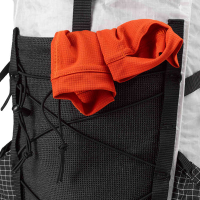 An ultralight mid layer hanging out of the Dyneema® stretch mesh front pocket on the Hyperlite Mountain Gear Elevate 22