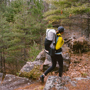 Hiker descends a rocky trail in the forest wearing the Hyperlite Mountain Gear Packs Unbound 55