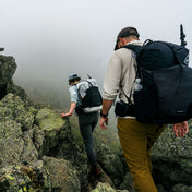 Hikers descend a rocky moss covered section of trail amidst thick fog wearing the Hyperlite Mountain Gear Waypoint 35