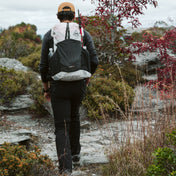 Hiker wearing the Hyperlite Mountain Gear Waypoint 35 approaches a river crossing in a forested area