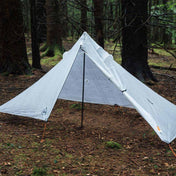 The Hyperlite Mountain Gear Mid 1 Tarp pitched and open at a campsite in the woods