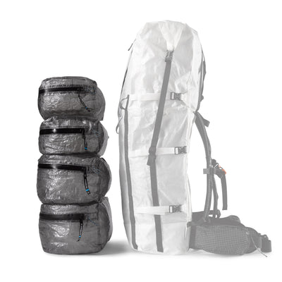 Four different sizes of the Hyperlite Mountain Gear Pods stacked next to one of the largest packs for a size comparison
