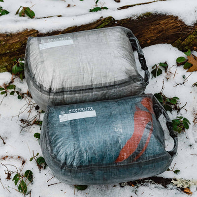 Top view of Hyperlite Mountain Gear's 12L and 15L Side Entry Pods on the snowy ground
