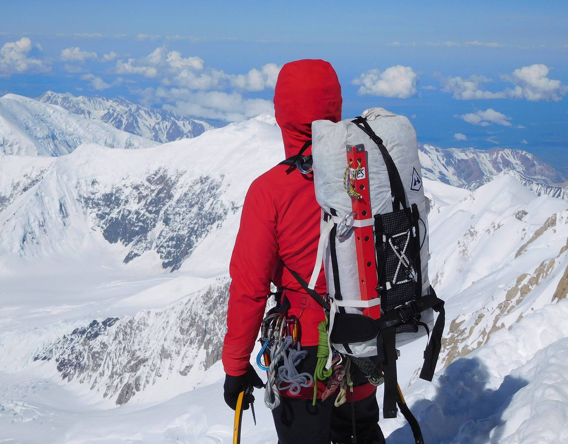 A man with a backpack standing on top of a snowy mountain.