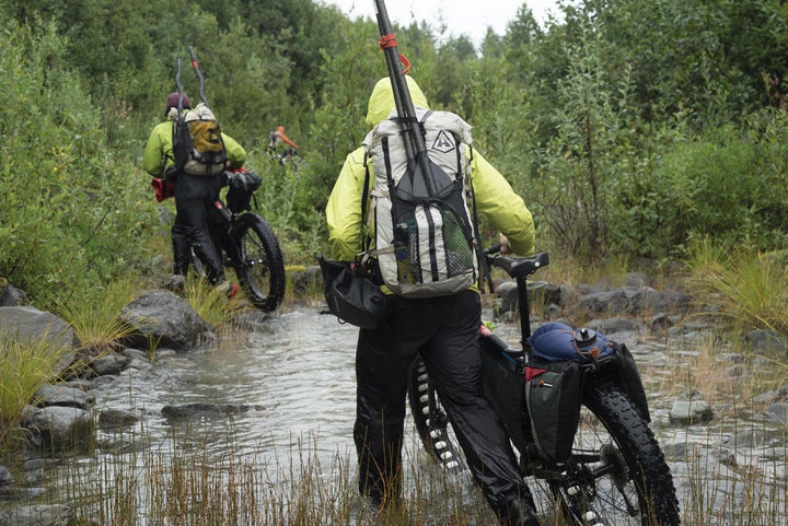 A group of people riding bikes through a muddy area.