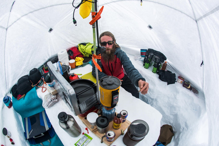 A man sitting in a tent with a cup of coffee.