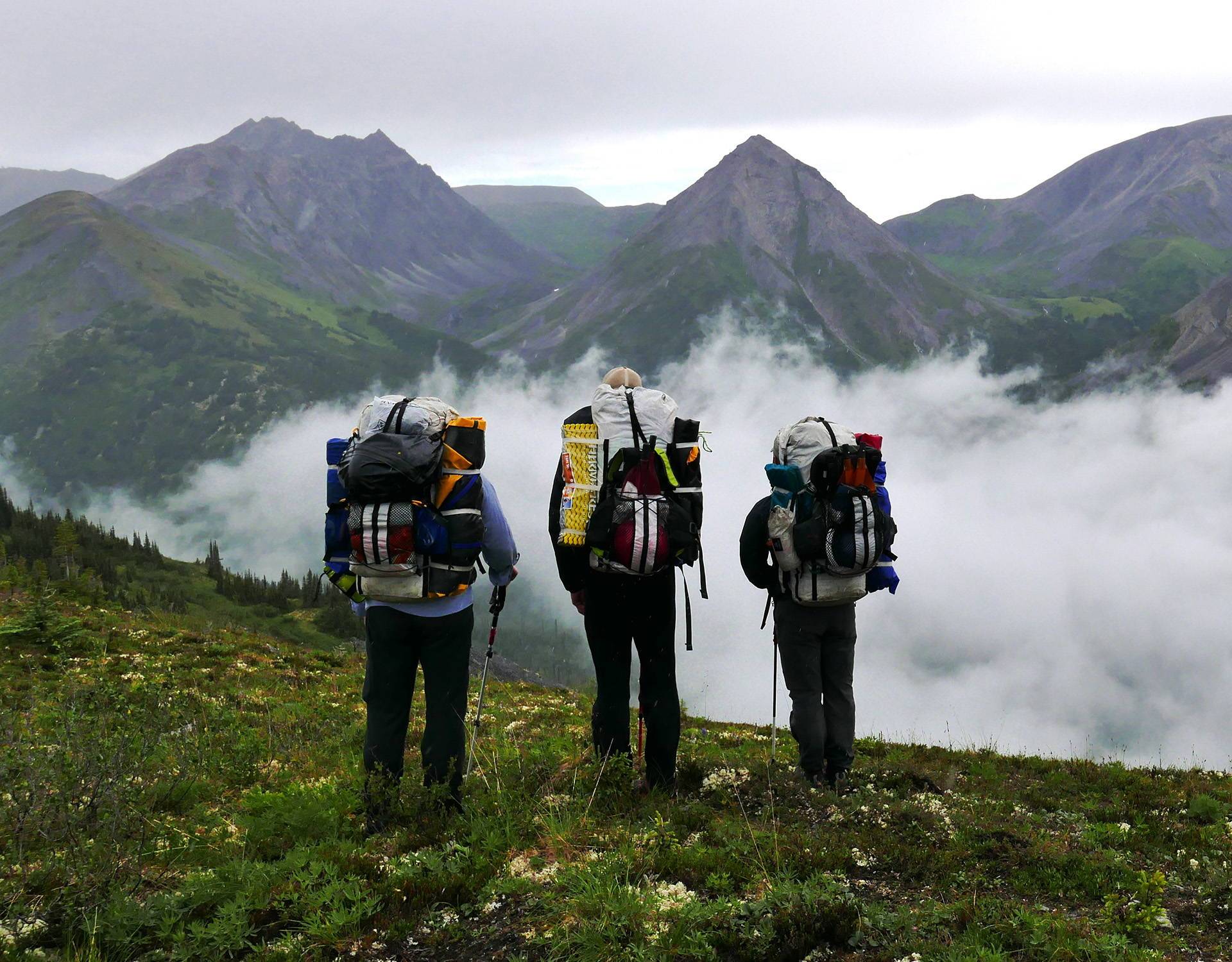 A group of people with backpacks standing on a mountain.