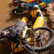 Hyperlite Mountain Gear's Porter 55 Pack in Black with a mountain bike on top of a kayak in a river