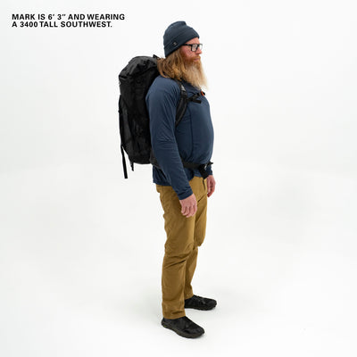 Male sporting a beard and showcasing the Black Southwest 55 backpack against a plain backdrop