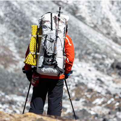 Back view of Hyperlite Mountain Gear's Ice Pack 70 in White on hiker in the snowy mountains