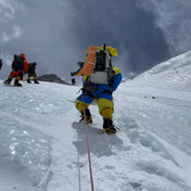 Hiker climbing an icy mountain wearing Hyperlite Mountain Gear's Ice Pack 70 Pack in White