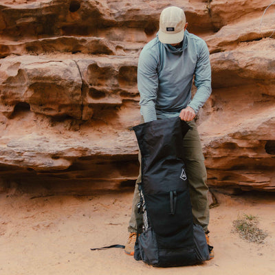 Hiker packs the Hyperlite Mountain Gear Unbound 55 by first unrolling the roll top closure system