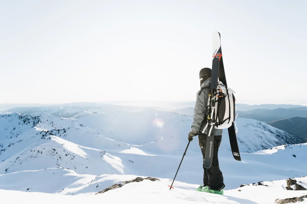 A skier standing on top of a mountain with his skis.