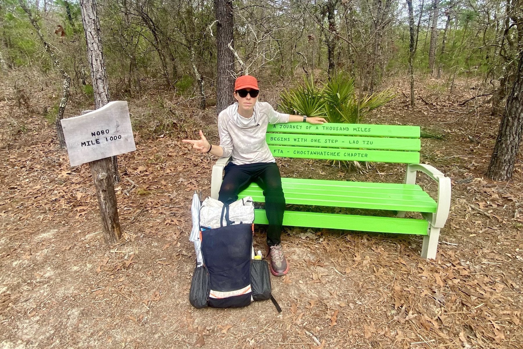 Tina Currin sits on a bench at mile marker 1000 with a Hyperlite Mountain Gear pack
