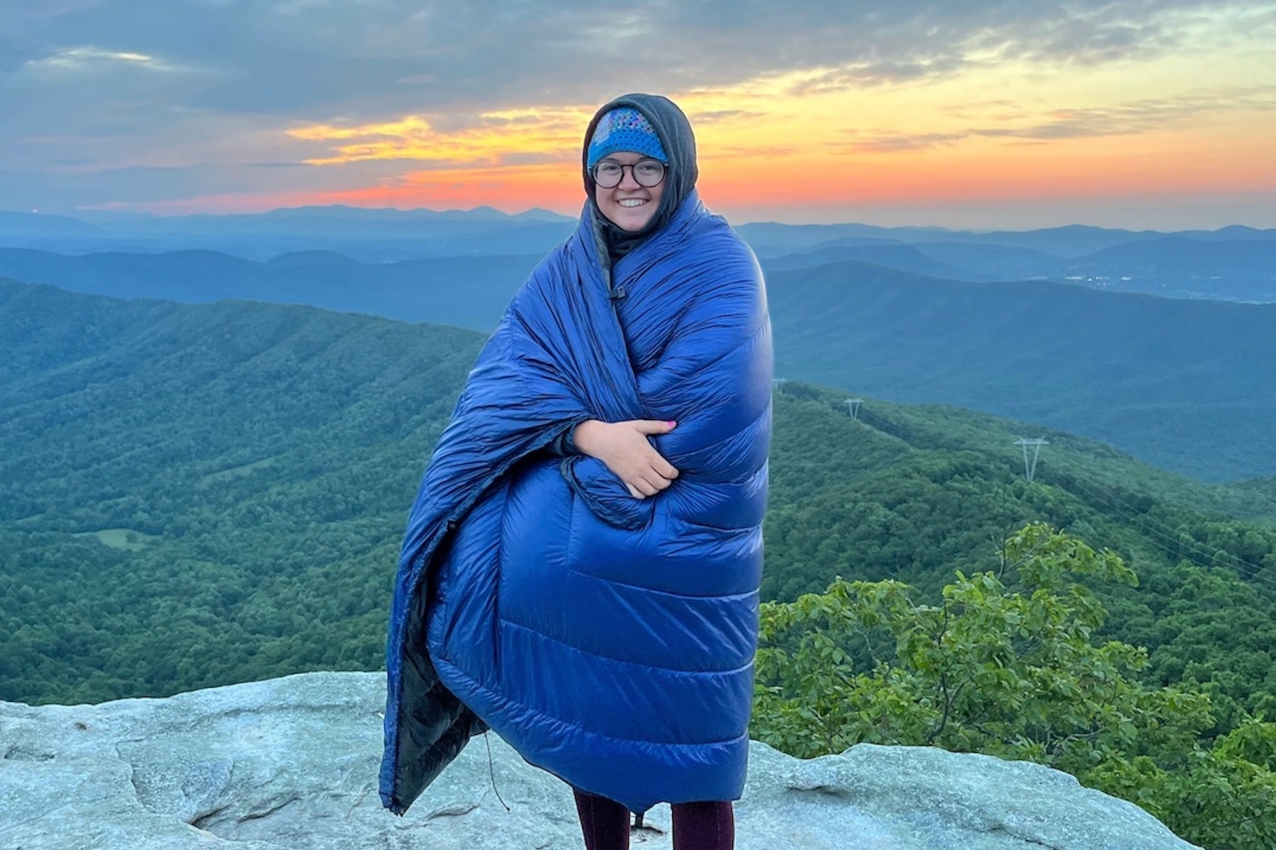 Camper waking up, wrapped in a sleeping bag at the summit