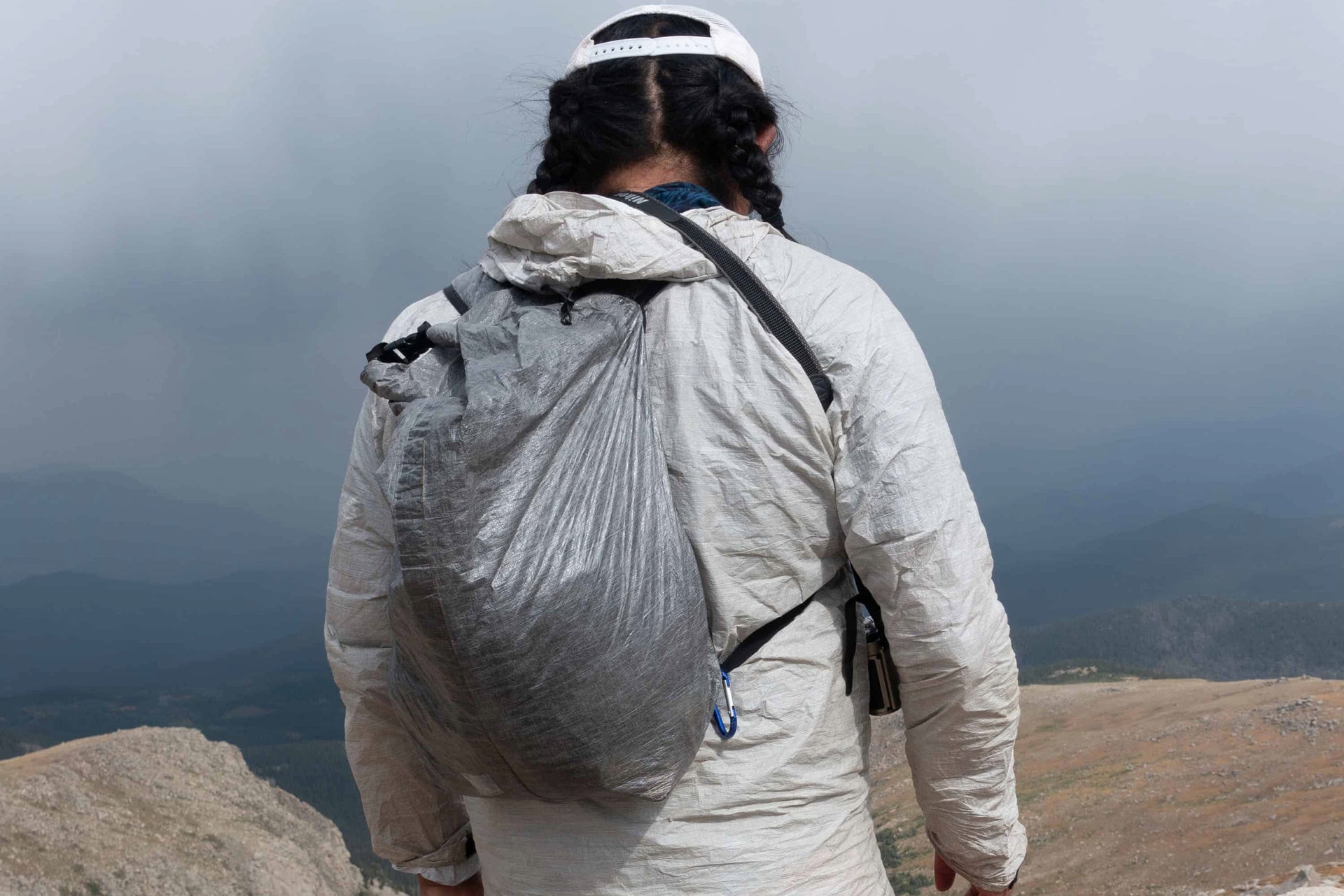 A man standing on top of a mountain with a backpack.