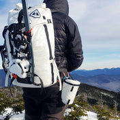 View of a hikers back with a pack on showing the Hyperlite Mountain Gear Camera Pod attached to a harness
