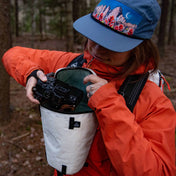 Hiker removes a camera from the Hyperlite Mountain Gear Camera Pod as it is strapped to their chest