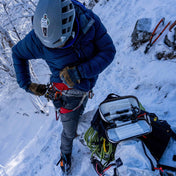 Alpine climber using Hyperlite Mountain Gear's Prism Ice Screw Case in White on snowy mountains