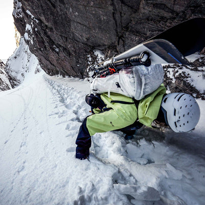 A mountaineer ascends a snowy ridge while using the Hyperlite Mountain Gear Diagonal Carry Kit
