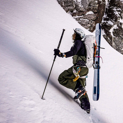 A mountaineer using the Hyperlite Mountain Gear Diagonal Carry Kit ascends a snowy slope