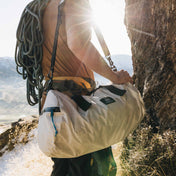 A climber with a rope slung over their back carries the Hyperlite Mountain Gear 30L Approach Duffel to the base of a climb