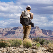 Hiker using the Southwest 55 backpack with trekking poles on a rocky landscape