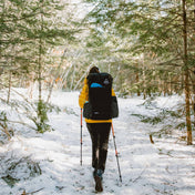 A hiker wearing the Hyperlite Mountain Gear Unbound 40 Pack treks through the snowy forest
