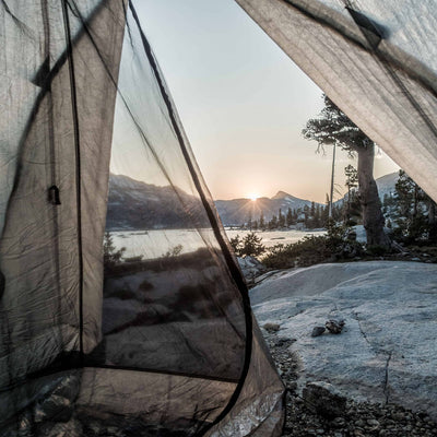 View from the interior of Hyperlite Mountain Gear Shelters UltaMid 2 Half Insert in white tent overlooking a mountain lake at sunrise