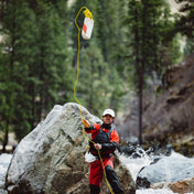 An action shot of a kayaker tossing the Hyperlite Mountain Gear River Rescue Throw Bag into a river