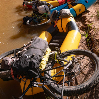Hyperlite Mountain Gear's Porter 40 Pack in Black with a mountain bike on top of a kayak in a river