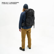 Hiker modeling the Black Hyperlite Mountain Gear Southwest 55 Liter backpack against a plain backdrop