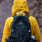 Back view of Hyperlite Mountain Gear's Daybreak 17 Pack in Black on hiker wearing a yellow coat