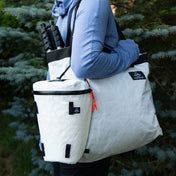 A hiker in the forest carrying the Camera Pod and GOAT Tote as part of the Hyperlite Mountain Gear Perfect Shot Bundle