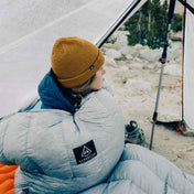 Camper wakes up in the tent bundled up in the Hyperlite Mountain Gear 20 Degree Quilt